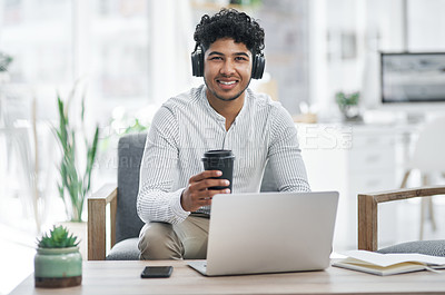 Buy stock photo Portrait of a young businessman drinking coffee while working on a laptop in an office