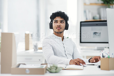 Buy stock photo Shot of a young businessman looking thoughtful while working on a computer in an office