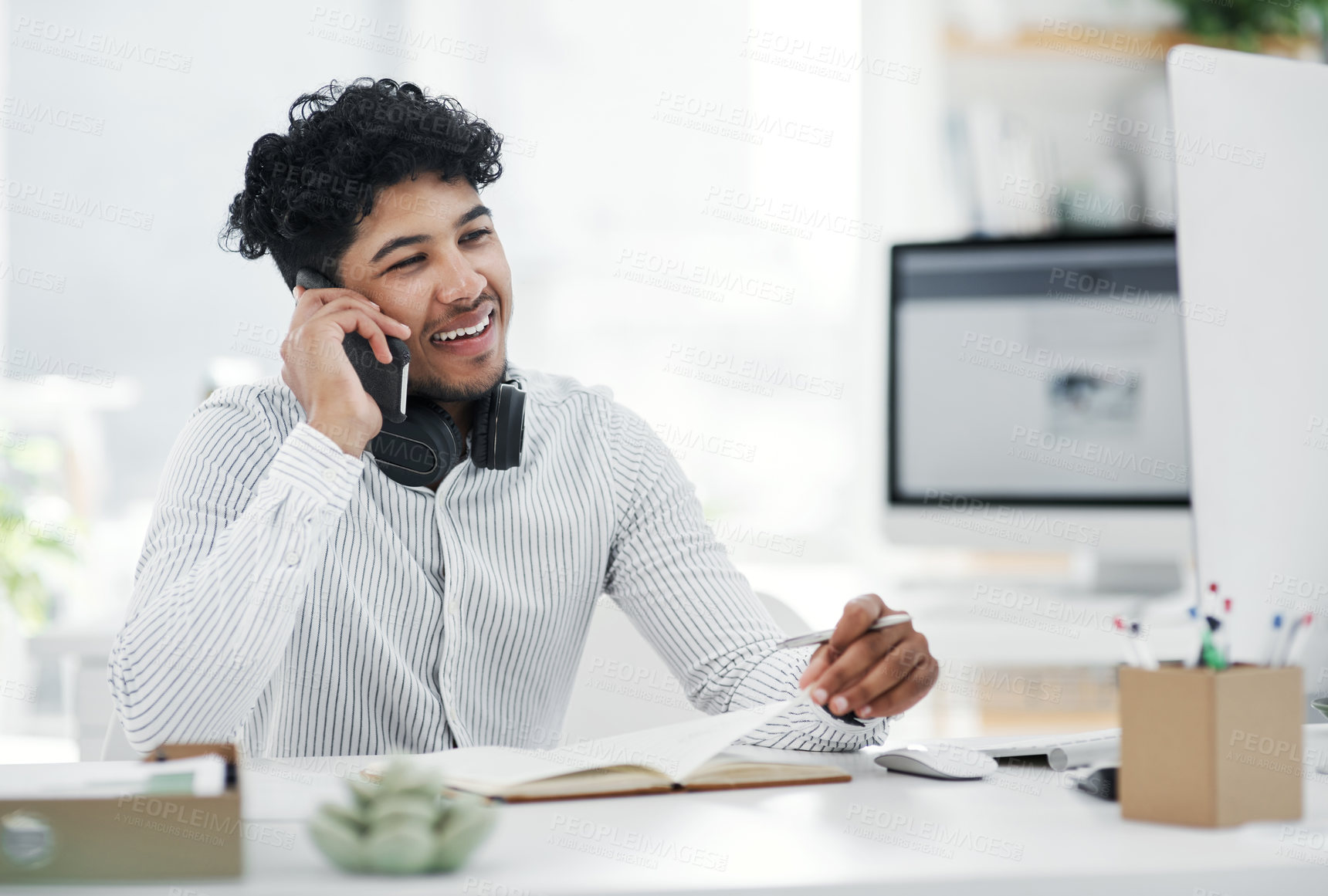 Buy stock photo Shot of a young businessman talking on a cellphone in an office