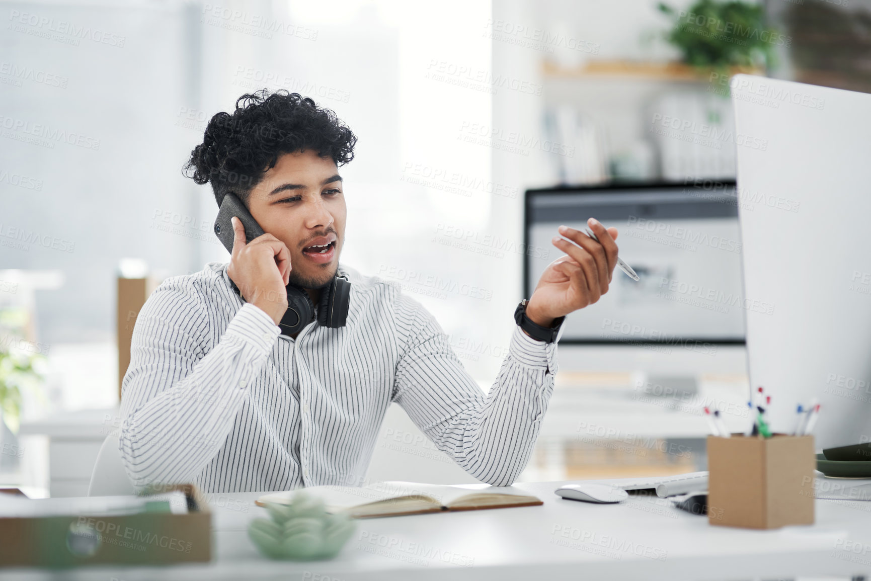 Buy stock photo Shot of a young businessman talking on a cellphone in an office