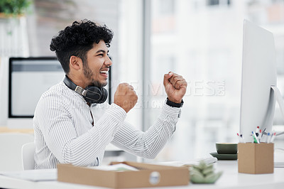 Buy stock photo Shot of a young businessman cheering while working on a computer in an office