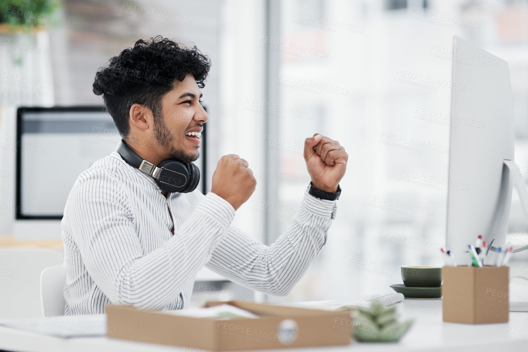 Buy stock photo Shot of a young businessman cheering while working on a computer in an office