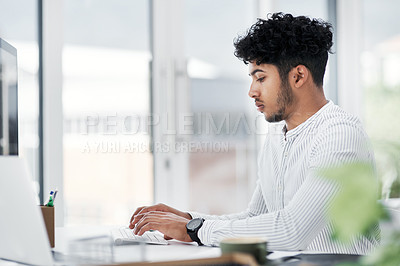 Buy stock photo Shot of a young businessman working on a computer in an office