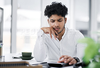 Buy stock photo Shot of a young businessman looking stressed out while using a calculator in an office