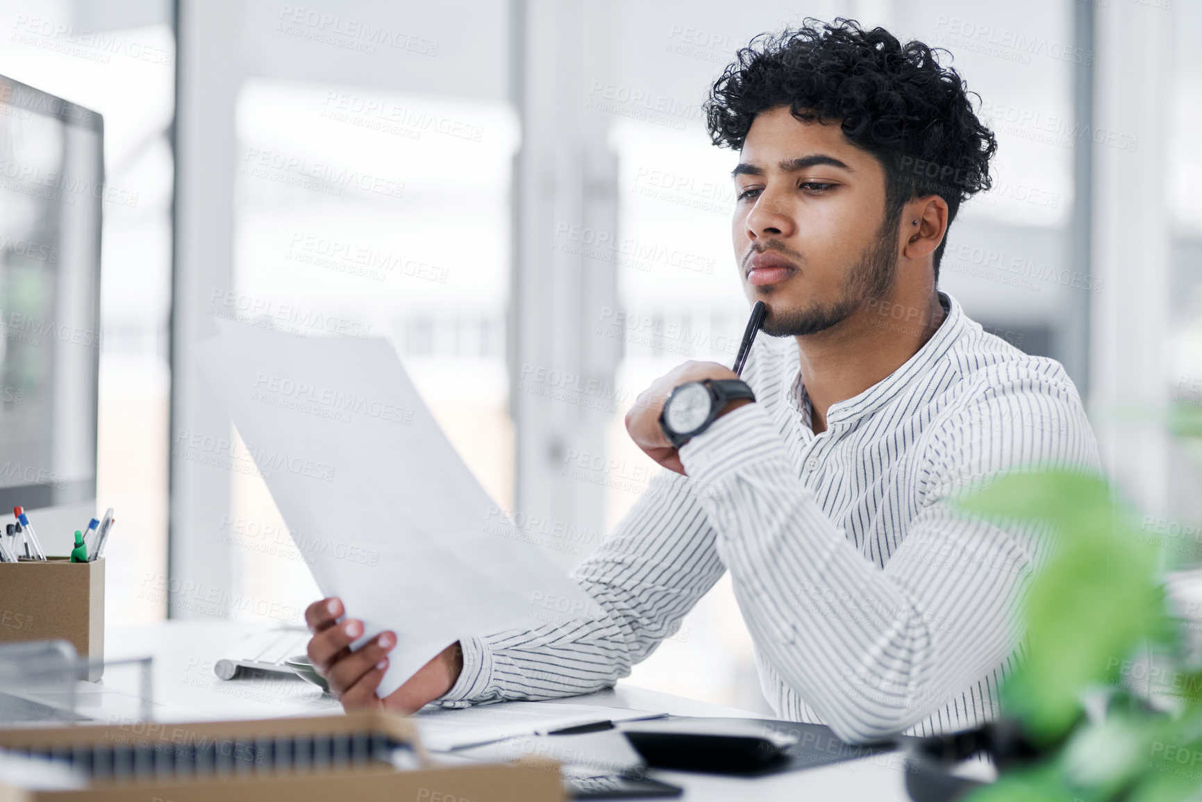 Buy stock photo Shot of a young businessman going through paperwork in an office