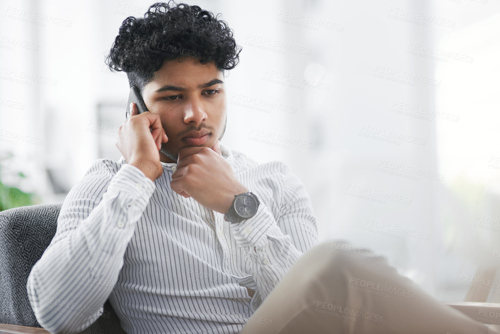 Buy stock photo Shot of a young businessman looking thoughtful while talking on a cellphone in an office