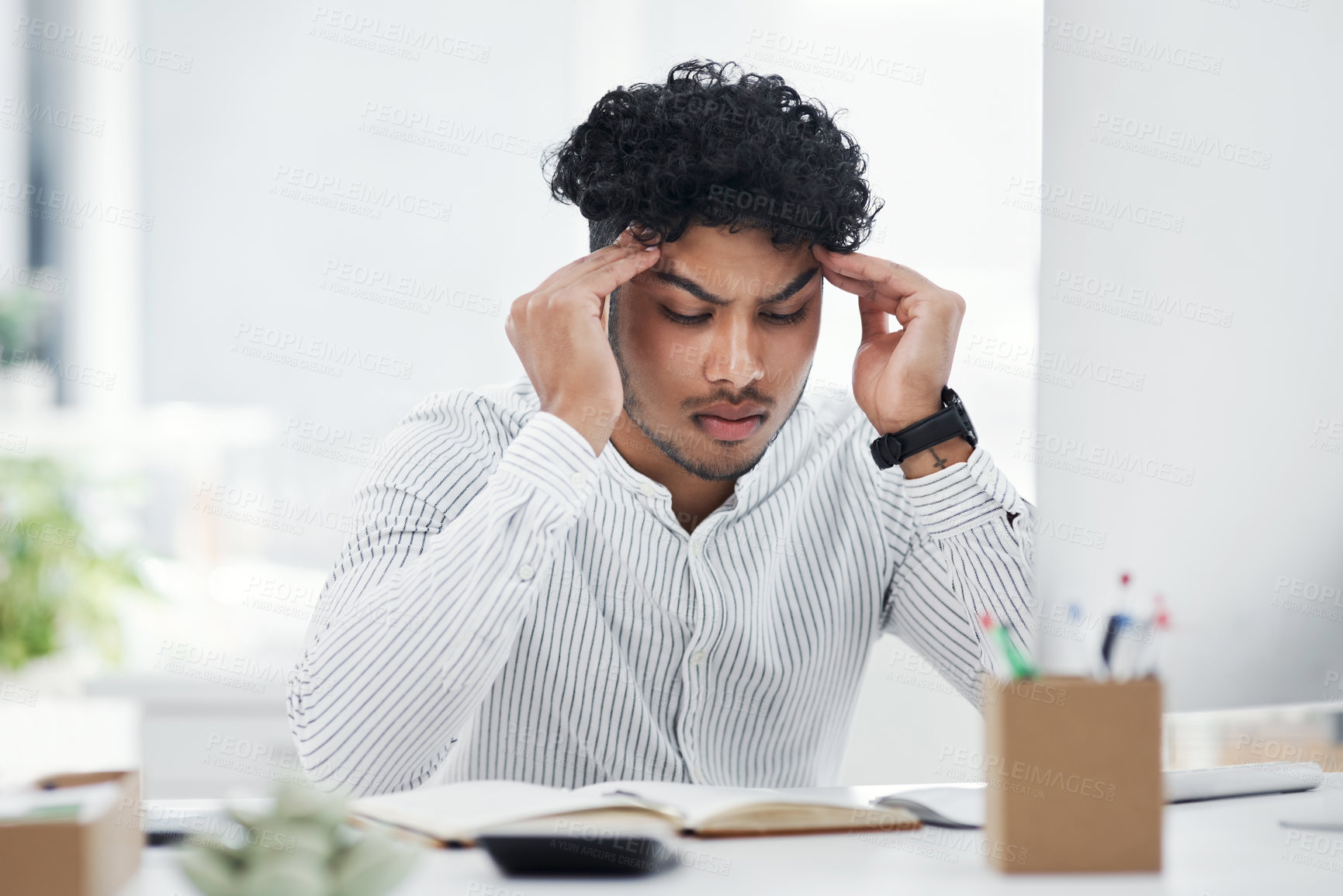 Buy stock photo Shot of a young businessman looking stressed out while working in an office