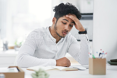 Buy stock photo Shot of a young businessman looking stressed out while working in an office