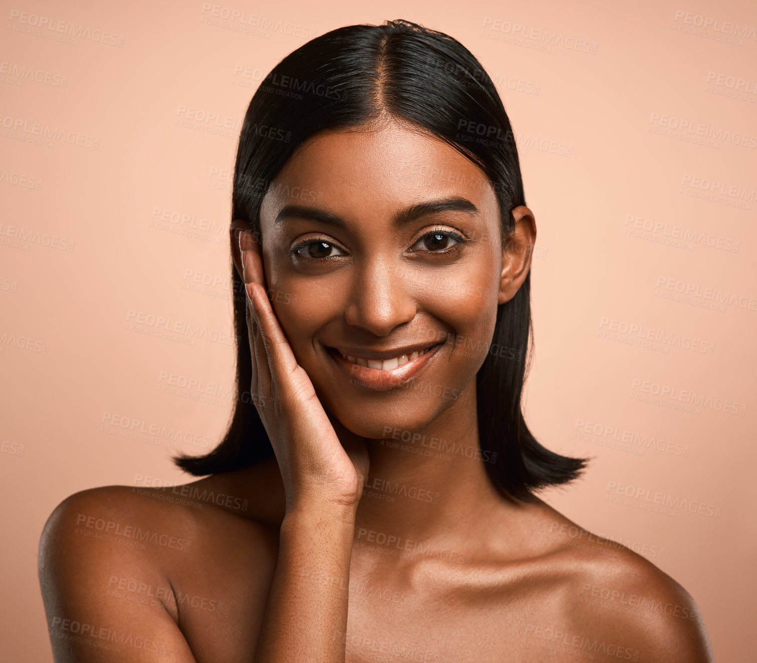 Buy stock photo Portrait of a beautiful young woman touching her face while posing against a brown background