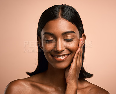 Buy stock photo Shot of a beautiful young woman touching her face while posing against a brown background