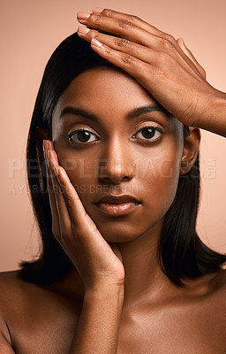 Buy stock photo Portrait of a beautiful young woman touching her face while posing against a brown background