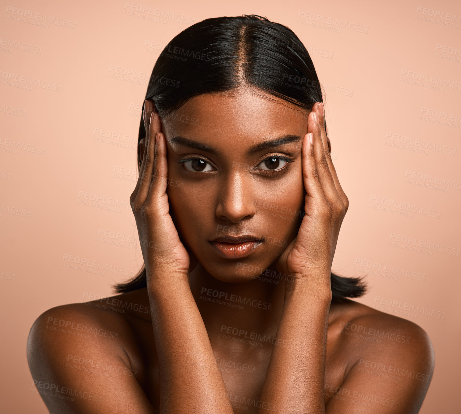 Buy stock photo Portrait of a beautiful young woman touching her face while posing against a brown background