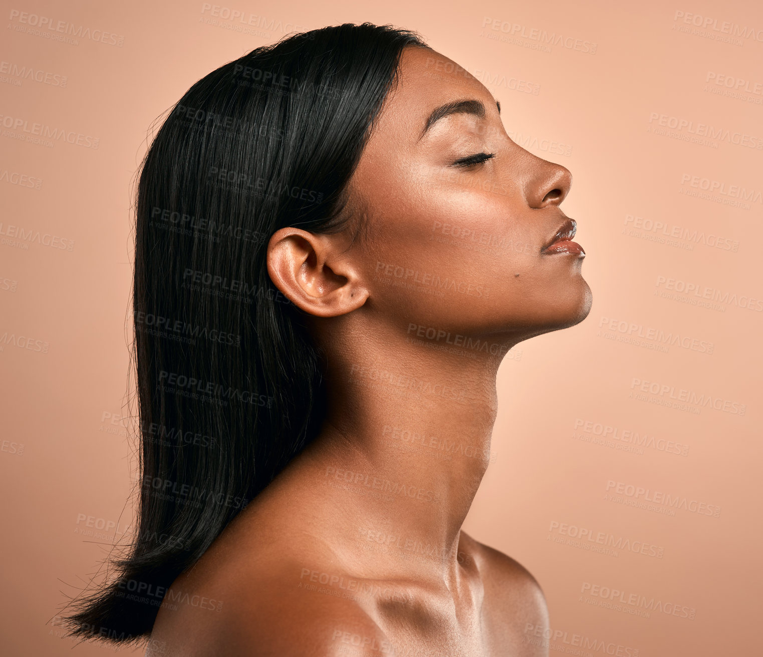 Buy stock photo Side shot of a beautiful young woman posing against a brown background