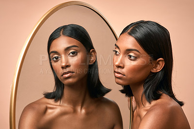 Buy stock photo Portrait of a beautiful young woman looking at a mirror and  posing against a brown background