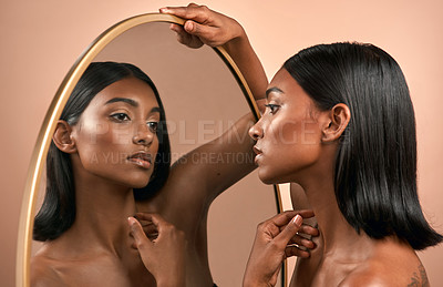 Buy stock photo Shot of a beautiful young woman looking at a mirror and  posing against a brown background