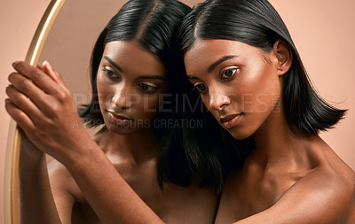 Buy stock photo Shot of a beautiful young woman holding a mirror and  posing against a brown background