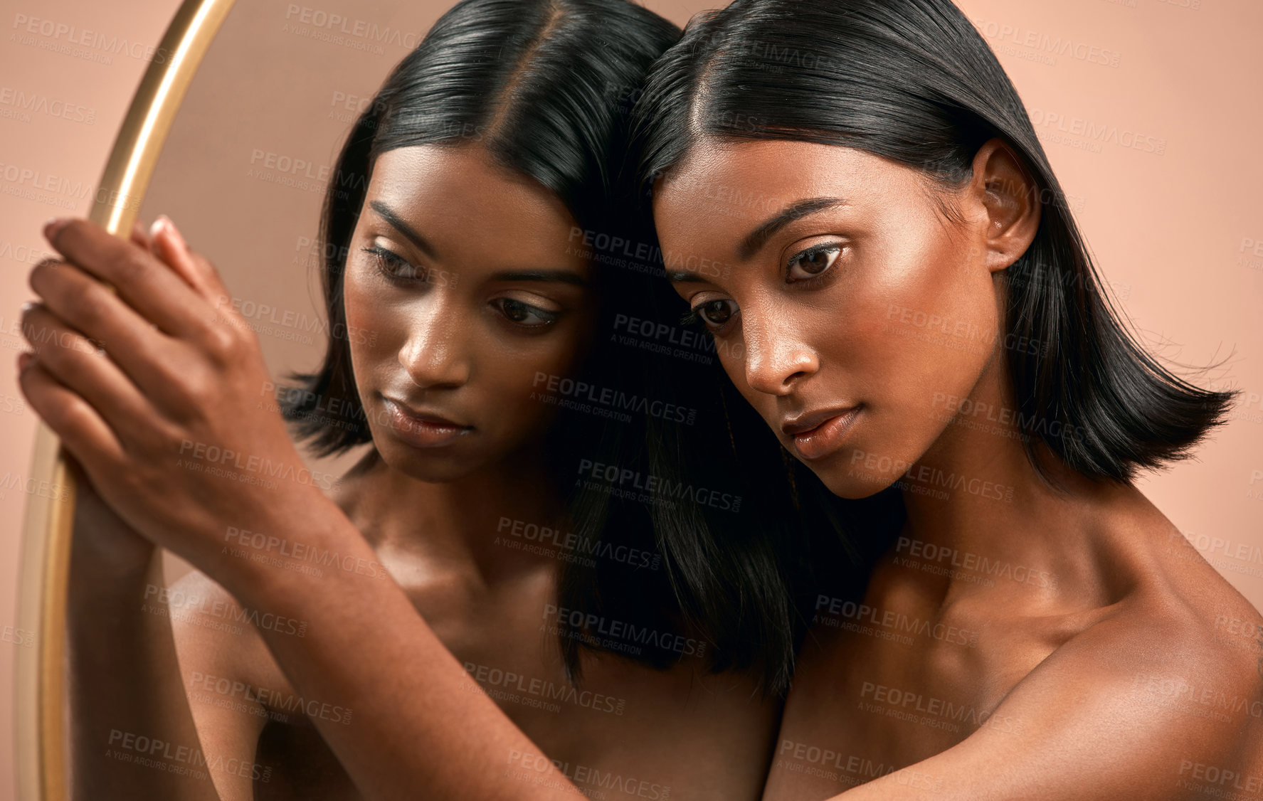 Buy stock photo Shot of a beautiful young woman holding a mirror and  posing against a brown background