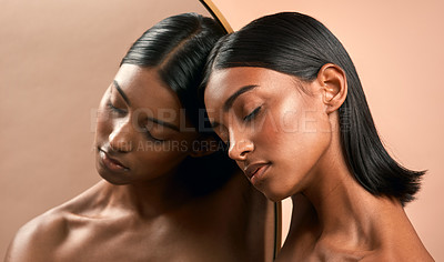 Buy stock photo Shot of a beautiful young woman resting her head on a mirror and posing against a brown background