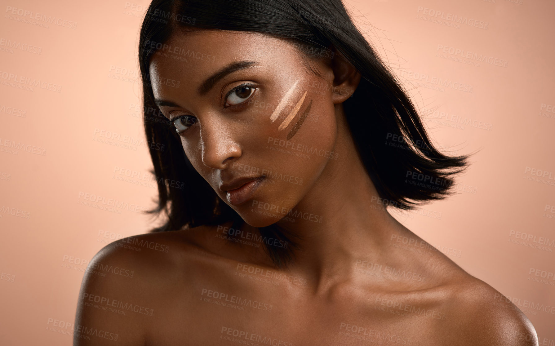 Buy stock photo Portrait of an attractive young woman applying foundation to her face against a brown background