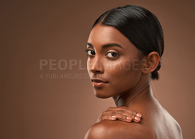 Buy stock photo Portrait of a beautiful young woman looking over her shoulder against a brown background