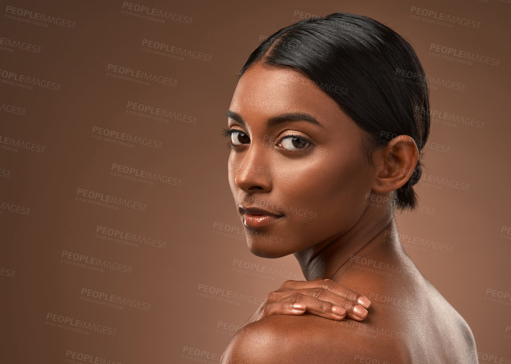 Buy stock photo Portrait of a beautiful young woman looking over her shoulder against a brown background
