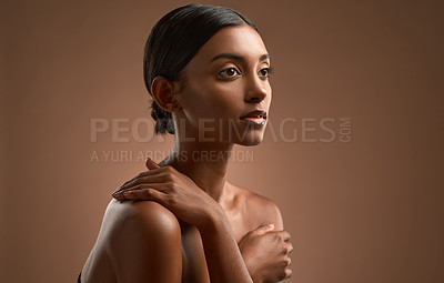 Buy stock photo Side shot of a beautiful young woman posing against a brown background