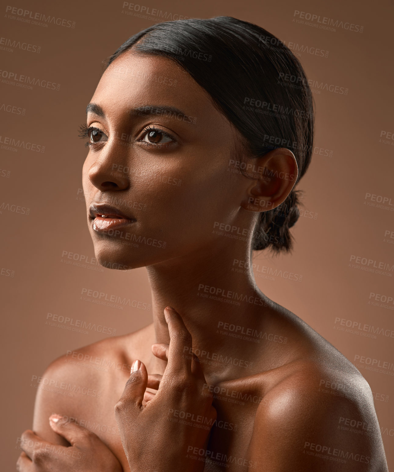 Buy stock photo Side shot of a beautiful young woman posing against a brown background