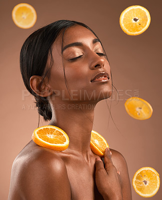 Buy stock photo Shot of a beautiful young woman surrounded by orange slices against a brown background