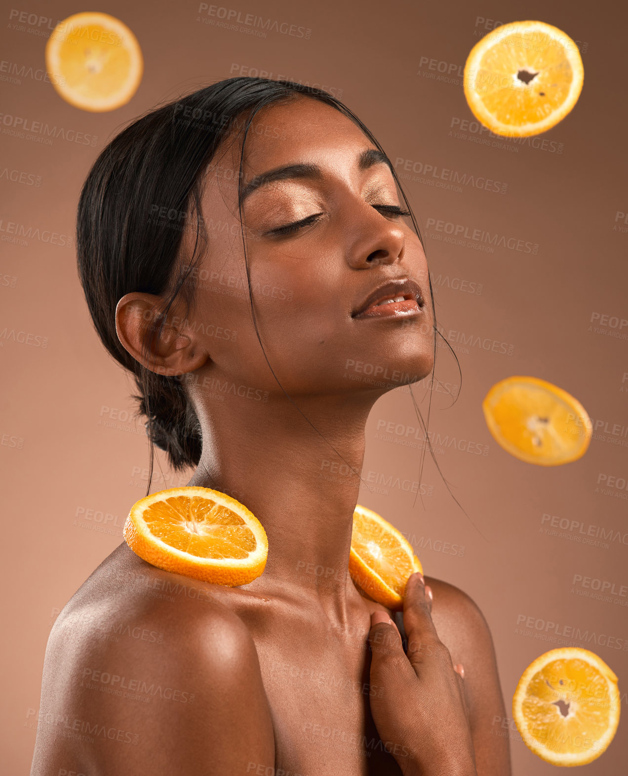 Buy stock photo Shot of a beautiful young woman surrounded by orange slices against a brown background