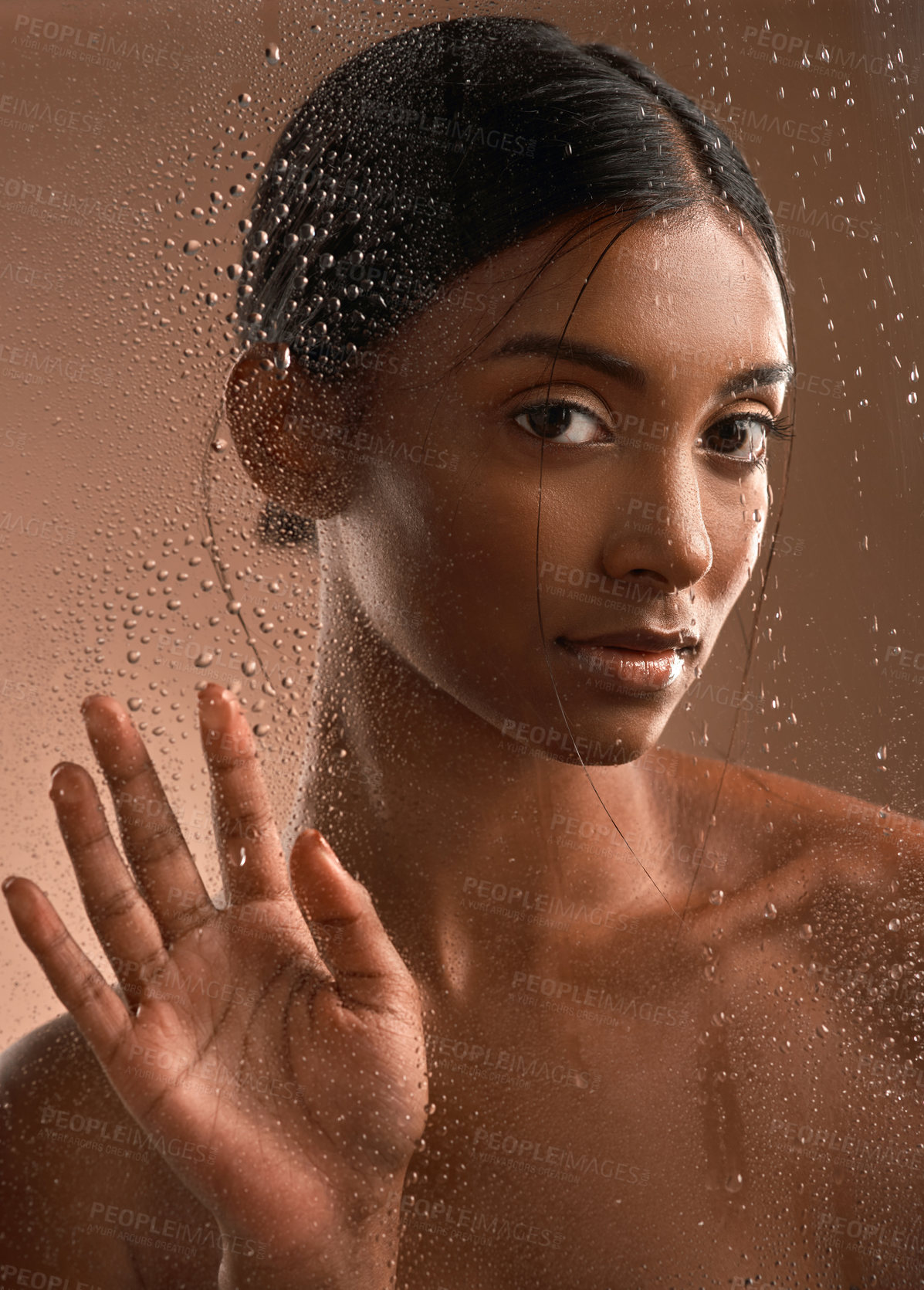 Buy stock photo Portrait of a beautiful young woman having a refreshing shower against a brown background