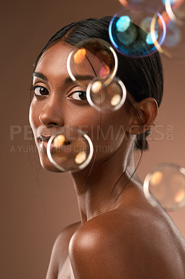 Buy stock photo Portrait of a young attractive woman posing with bubbles against a brown background