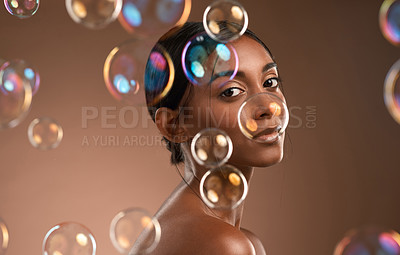 Buy stock photo Portrait of a young attractive woman posing with bubbles against a brown background