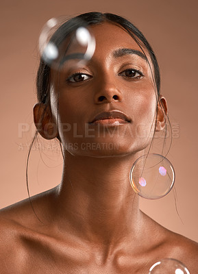 Buy stock photo Portrait of a young attractive woman posing with bubbles against a brown background