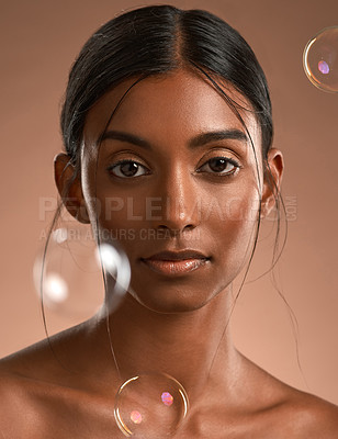 Buy stock photo Portrait of a young attractive woman posing with bubbles against a brown background