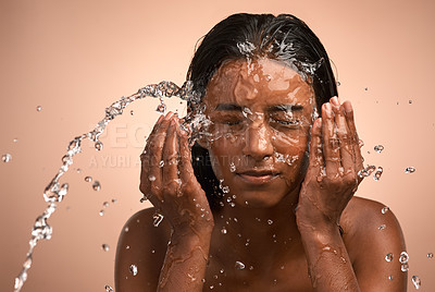 Buy stock photo Shot of a young attractive woman doing her daily skincare routine against a brown background