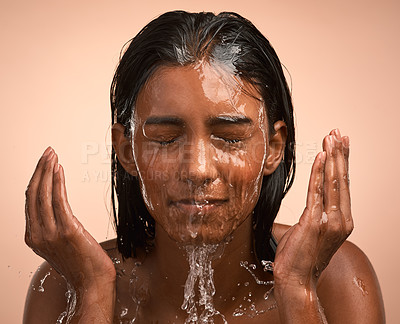 Buy stock photo Shot of a young attractive woman doing her daily skincare routine against a brown background