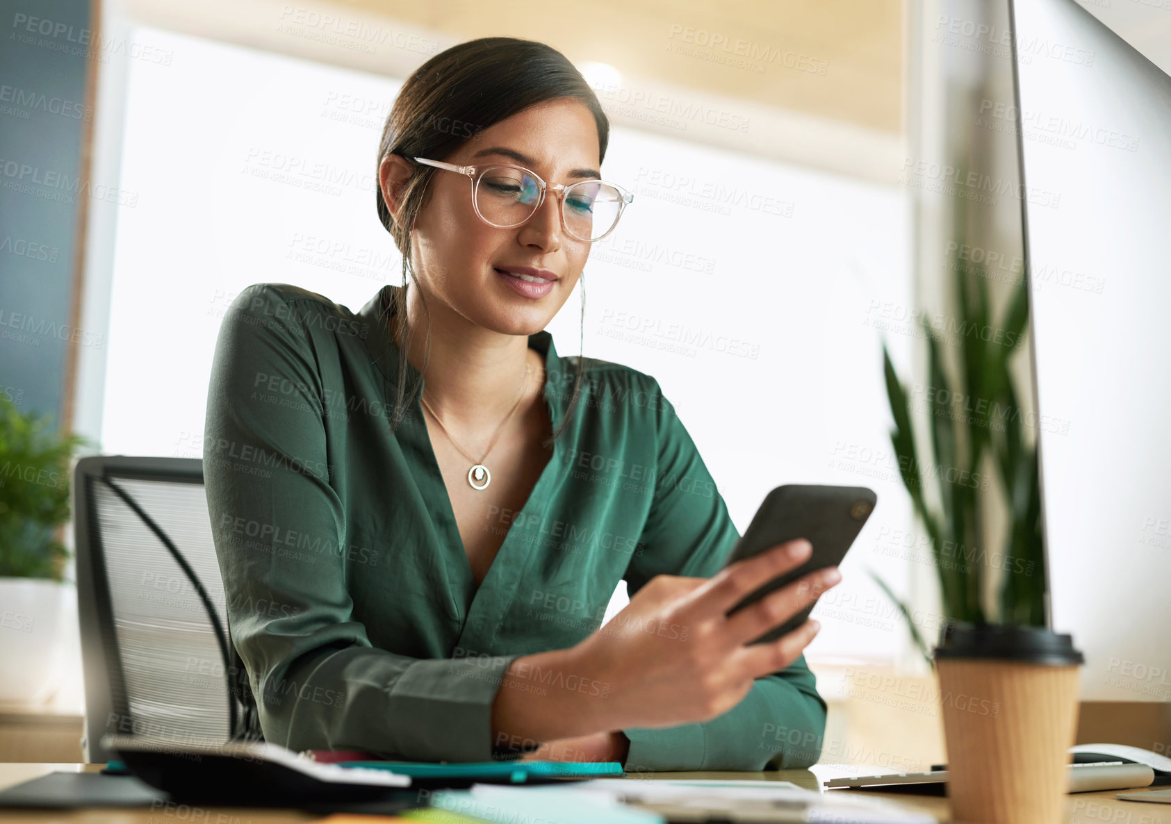 Buy stock photo Shot of a young businesswoman using her smartphone to send text messages