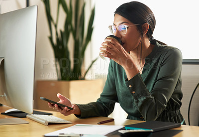 Buy stock photo Shot of a young businesswoman drinking coffee while using her smartphone