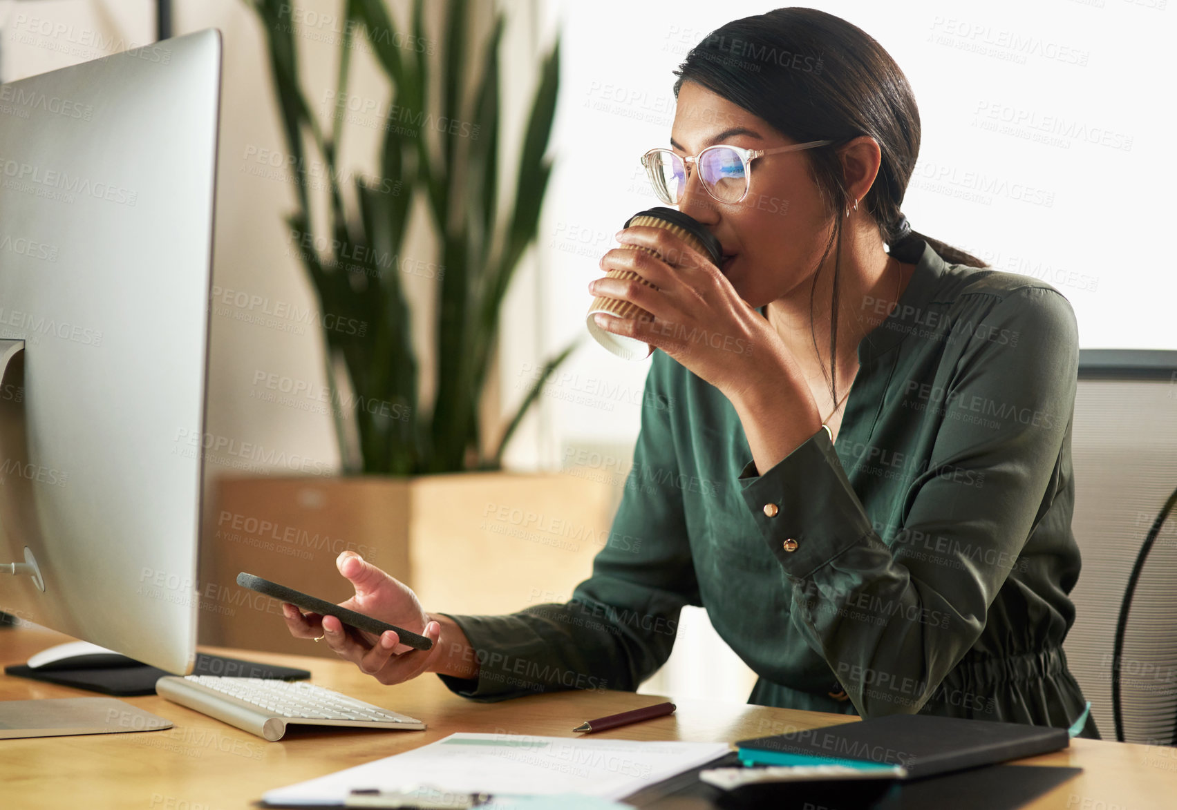 Buy stock photo Shot of a young businesswoman drinking coffee while using her smartphone