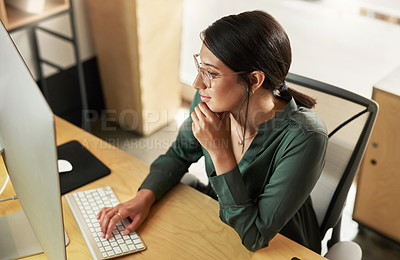 Buy stock photo Shot of a young businesswoman typing on her desktop PC keyboard while using her smartphone