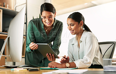 Buy stock photo Shot of two businesswomen using a digital tablet to oversee work