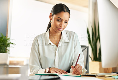 Buy stock photo Shot of a young businesswoman compiling notes at work