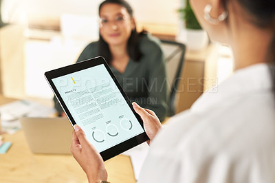 Buy stock photo Shot of two businesswomen using a digital tablet to oversee work