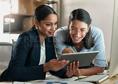 Buy stock photo Shot of two female coworkers using a digital tablet at work