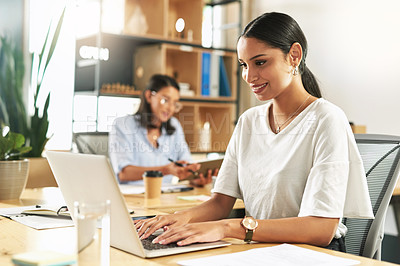 Buy stock photo Shot of a young businesswoman using her laptop at work