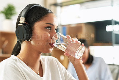 Buy stock photo Shot of a young businesswoman drinking a glass of water at work