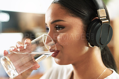 Buy stock photo Shot of a young businesswoman drinking a glass of water at work