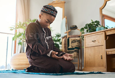 Buy stock photo Shot of a young muslim boy praying in the lounge at home