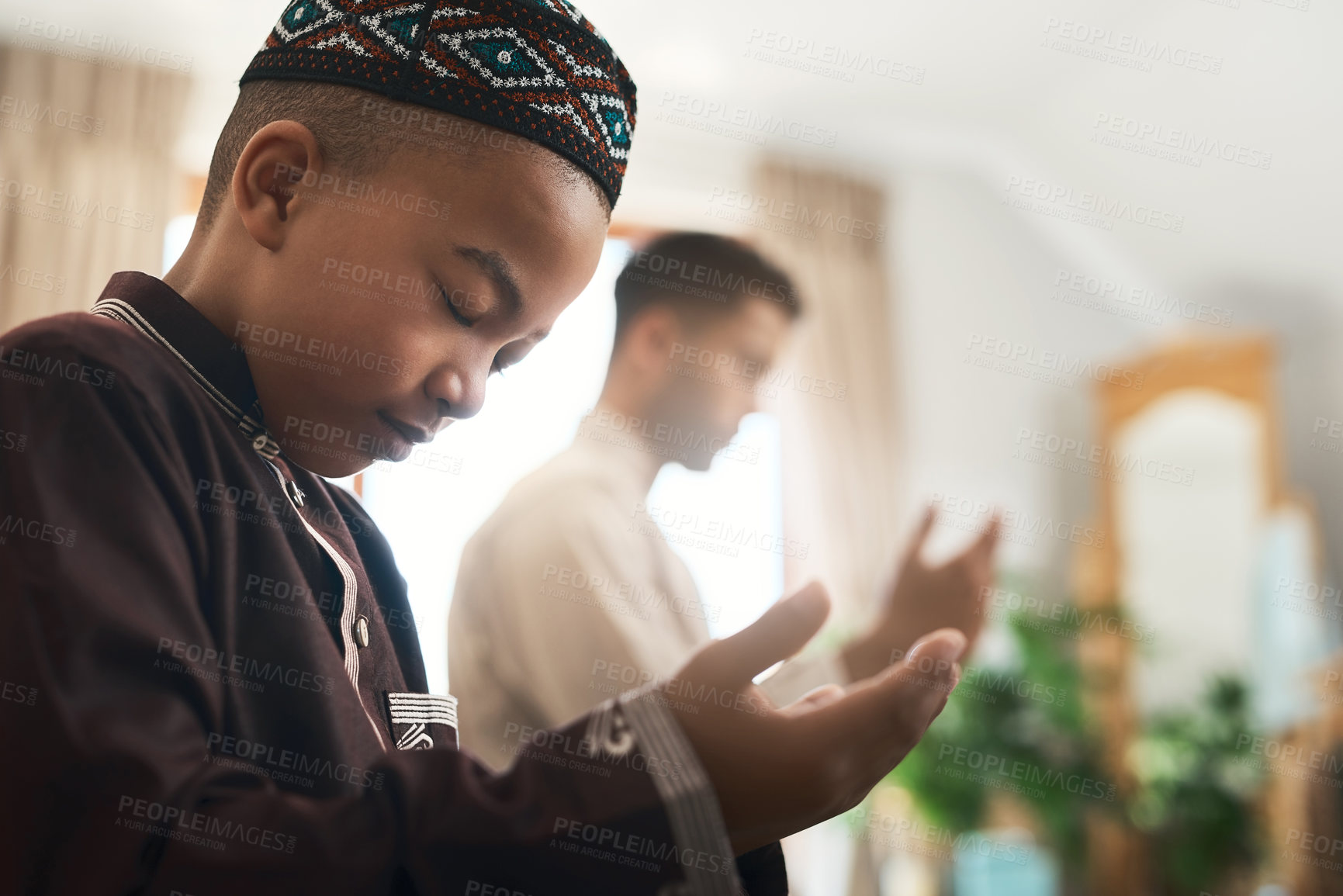 Buy stock photo Shot of a young muslim man and his son praying in the lounge at home