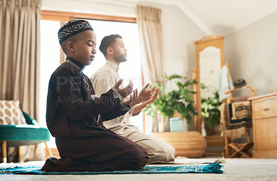 Buy stock photo Shot of a young muslim man and his son praying in the lounge at home